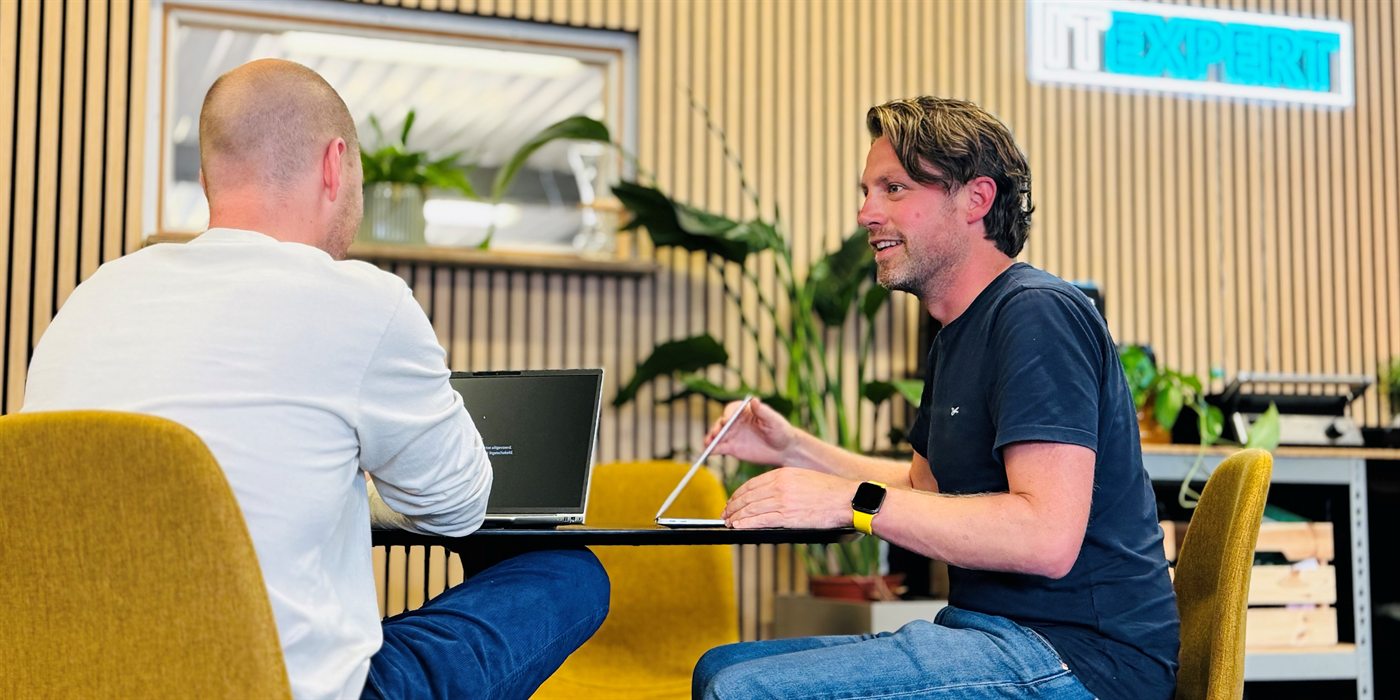 Twee collega's van IT Expert het Gooi in gesprek op kantoor